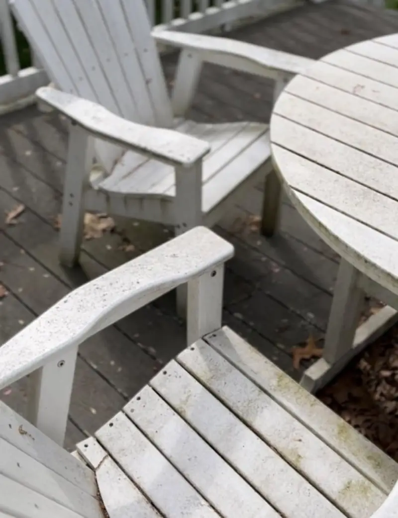 Before: white outdoor table and Adirondack-style chairs on a deck, dull and streaked with grime and green mildew