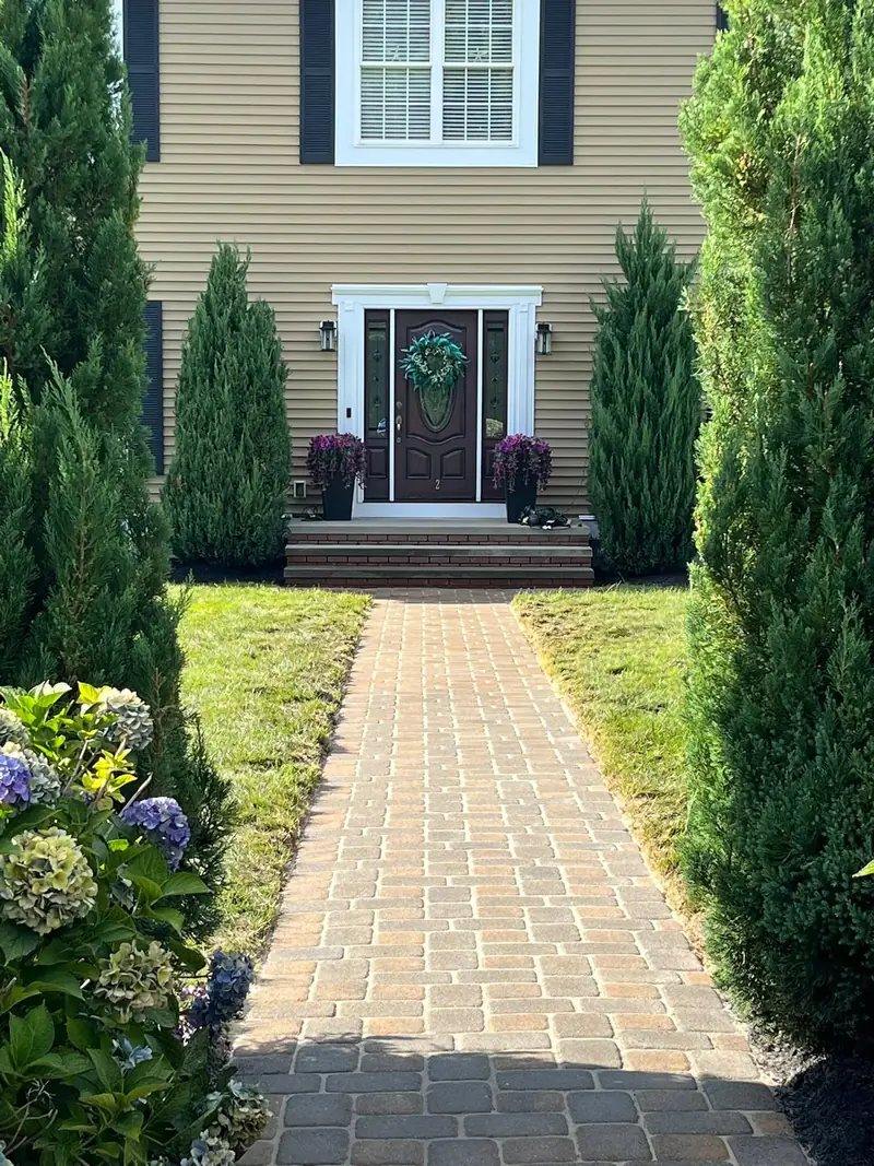 After: the same paver walkway cleaned, joints clear and pavers brighter, seen from closer to the front steps